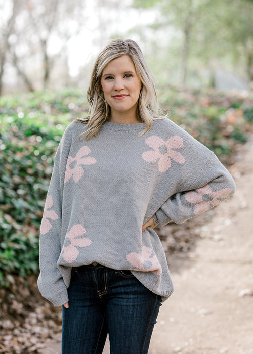 Blonde model wearing grey sweater with pink flowers.