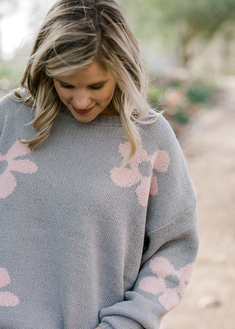 Close up of Blonde model wearing grey sweater with pink flowers.