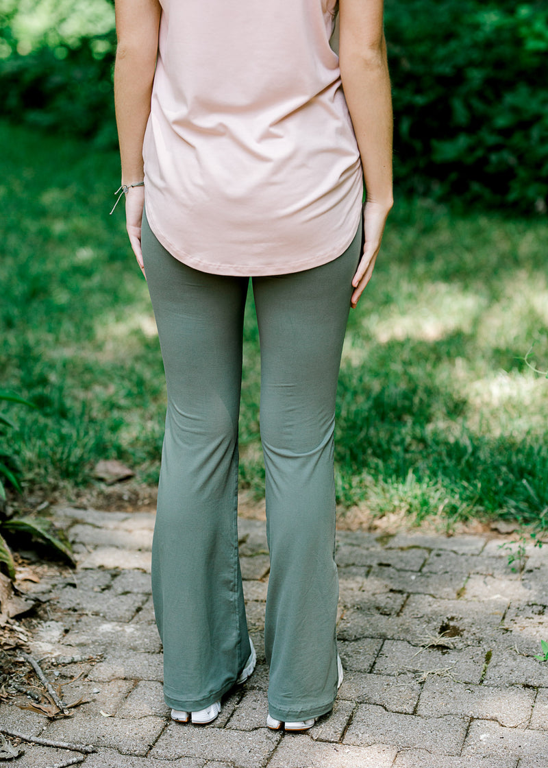 Back view of brunette model wearing sage grey flare legging and tank.