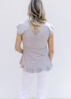 Back view of a v-neck with a tie on a model wearing a gray babydoll top and capped sleeves.