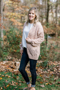 Blonde model wearing cream open weave cardigan with jeans and mules. 