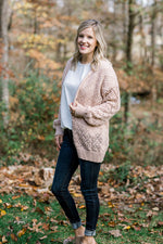 Blonde model wearing cream open weave cardigan with jeans and mules. 