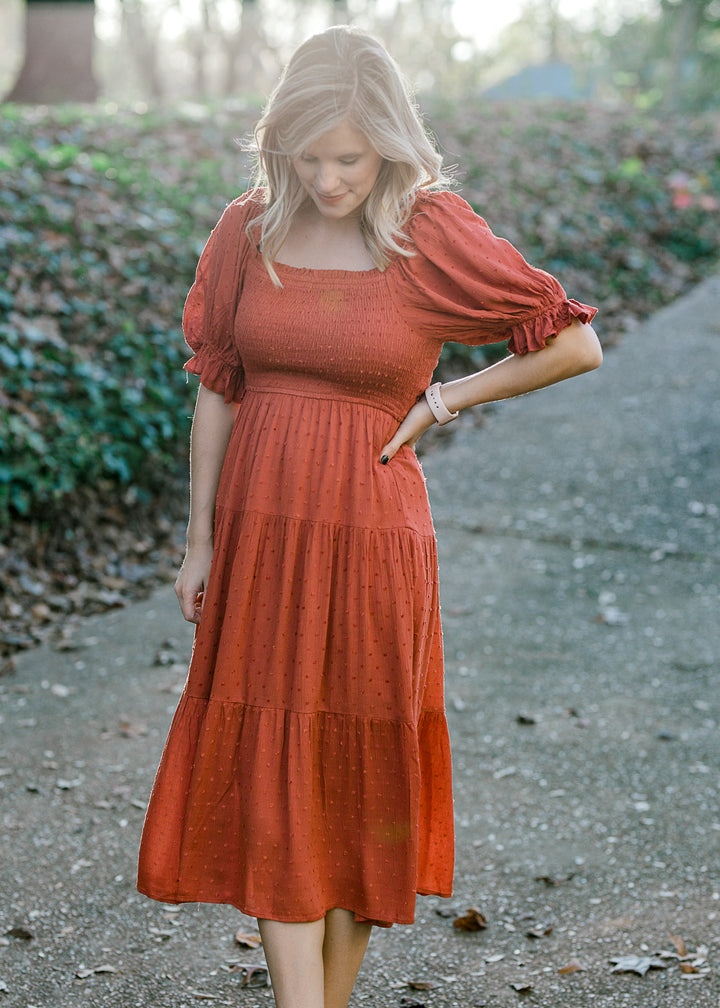 Blonde model wearing rust colored smocked dress.