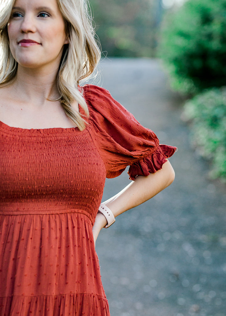 Close up of  Blonde model wearing rust colored smocked dress.