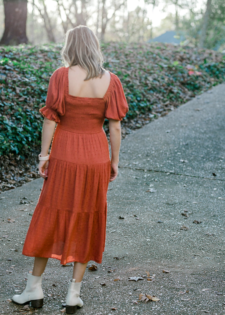 Back view of  Blonde model wearing rust colored smocked dress.