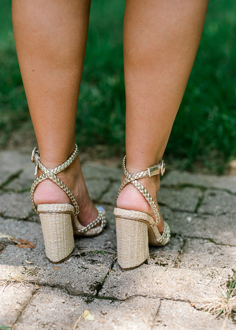 Back view of woven gold strap sandals with chunky rattan heels.