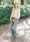 Blonde model wearing oatmeal blouse with hi-rise flair jeans.