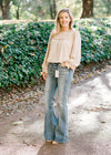 Blonde model wearing oatmeal blouse with hi-rise flair jeans with mules.