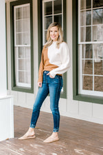 Model wearing double fray hem skinny jeans and white blouse.