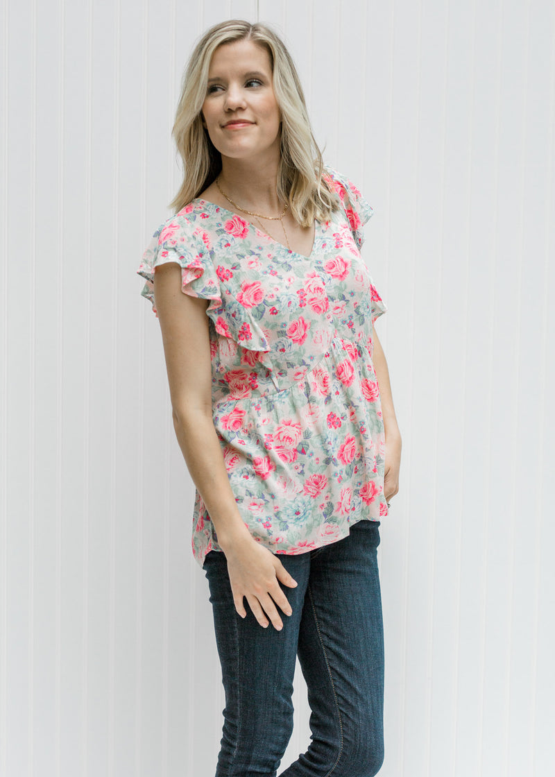 Blonde model wearing a pink floral top with jeans. 
