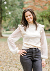 Brunette model wearing ivory colored sweater with lacework sleeves.