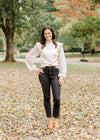 Brunette model wearing ivory colored sweater with lacework sleeves, jeans and booties.