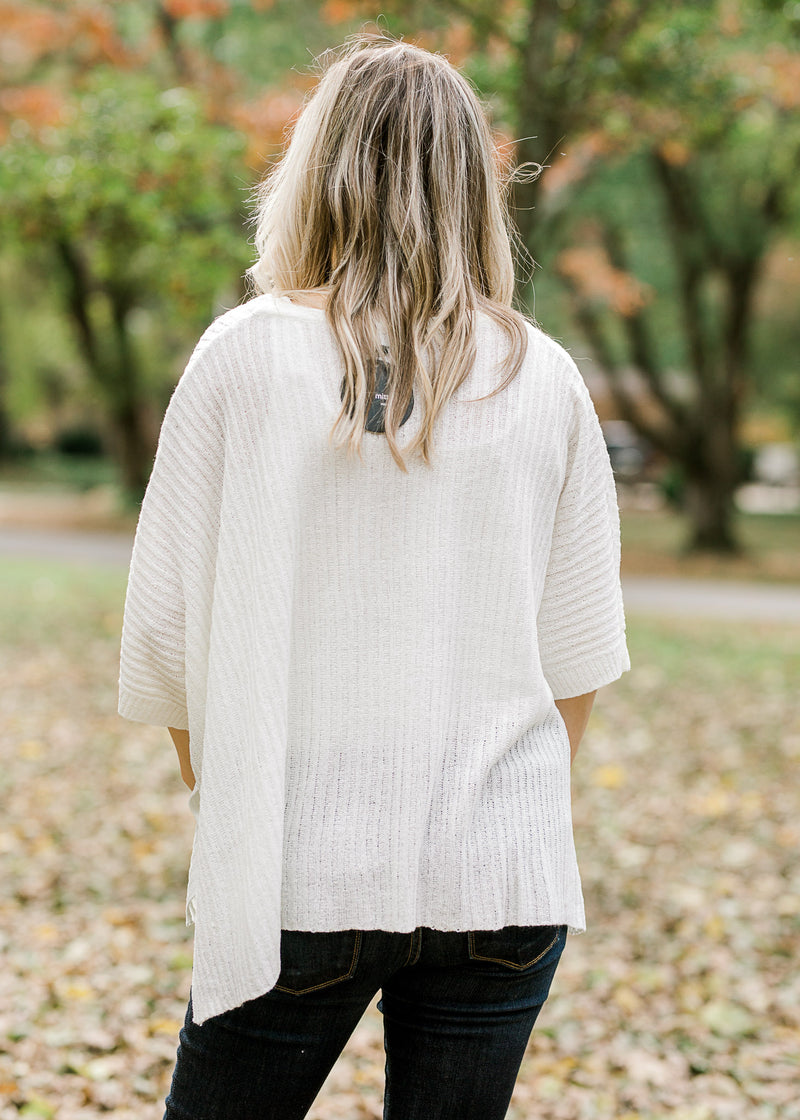 Back view of Blonde model wearing ivory cable knit sweater.