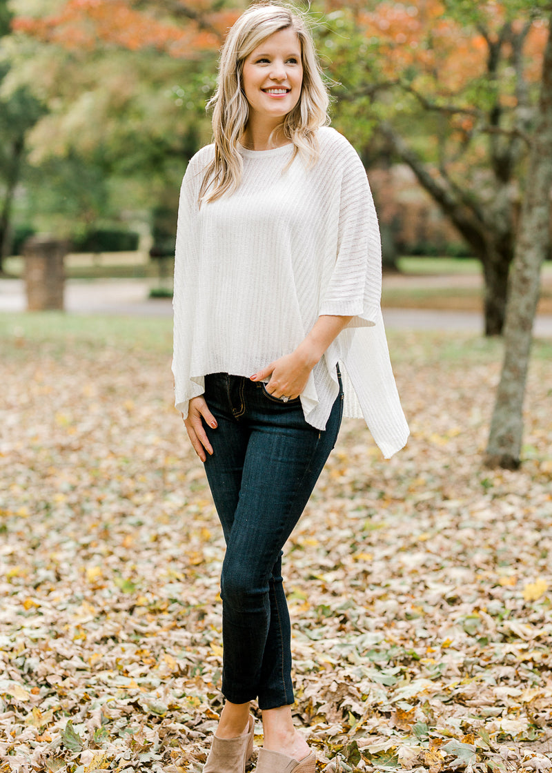 Blonde model wearing ivory cable knit sweater with jeans and mules.