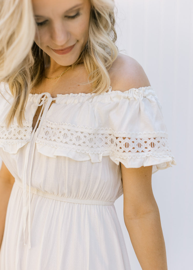 Close up view of lace detail and tie at neck of a cream midi dress with an elastic waistband. 