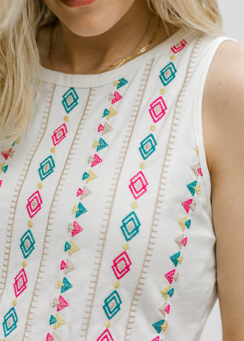 Close up view of  Blonde model wearing a white tank with Aztec embroidery