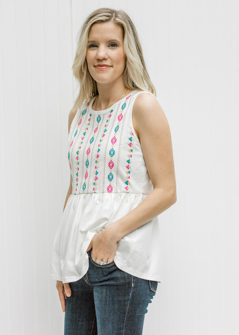Blonde model wearing a white tank with Aztec embroidery.