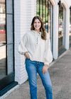 Brunette model wearing an ivory sweater. 