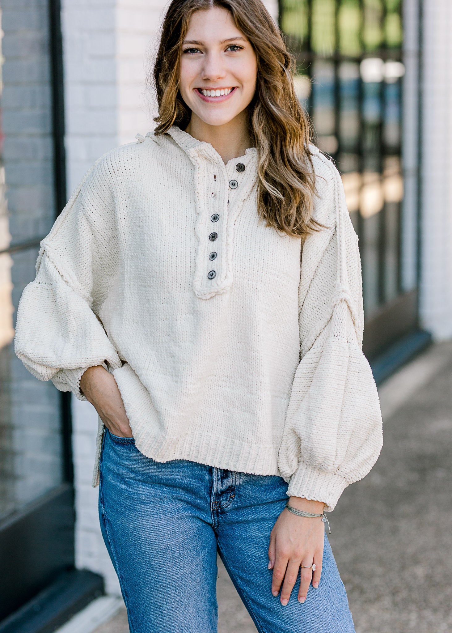 Brunette model wearing an ivory sweater with buttons.
