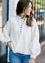Brunette model wearing an ivory sweater with bubble sleeves.