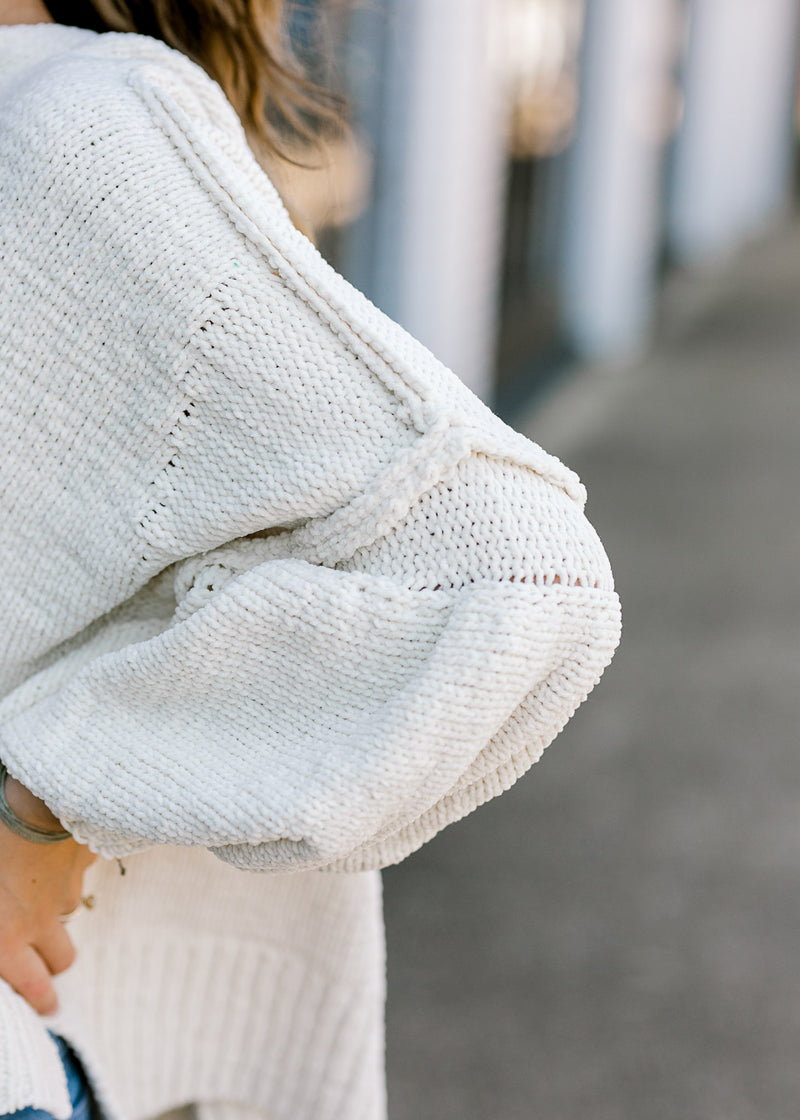 Close up view of bubble sleeve on ivory sweater.