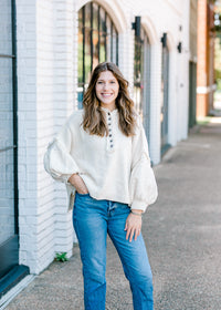 Brunette model wearing an ivory sweater with jeans.