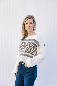 Blonde model wearing a cream sweater with a crop hem.  