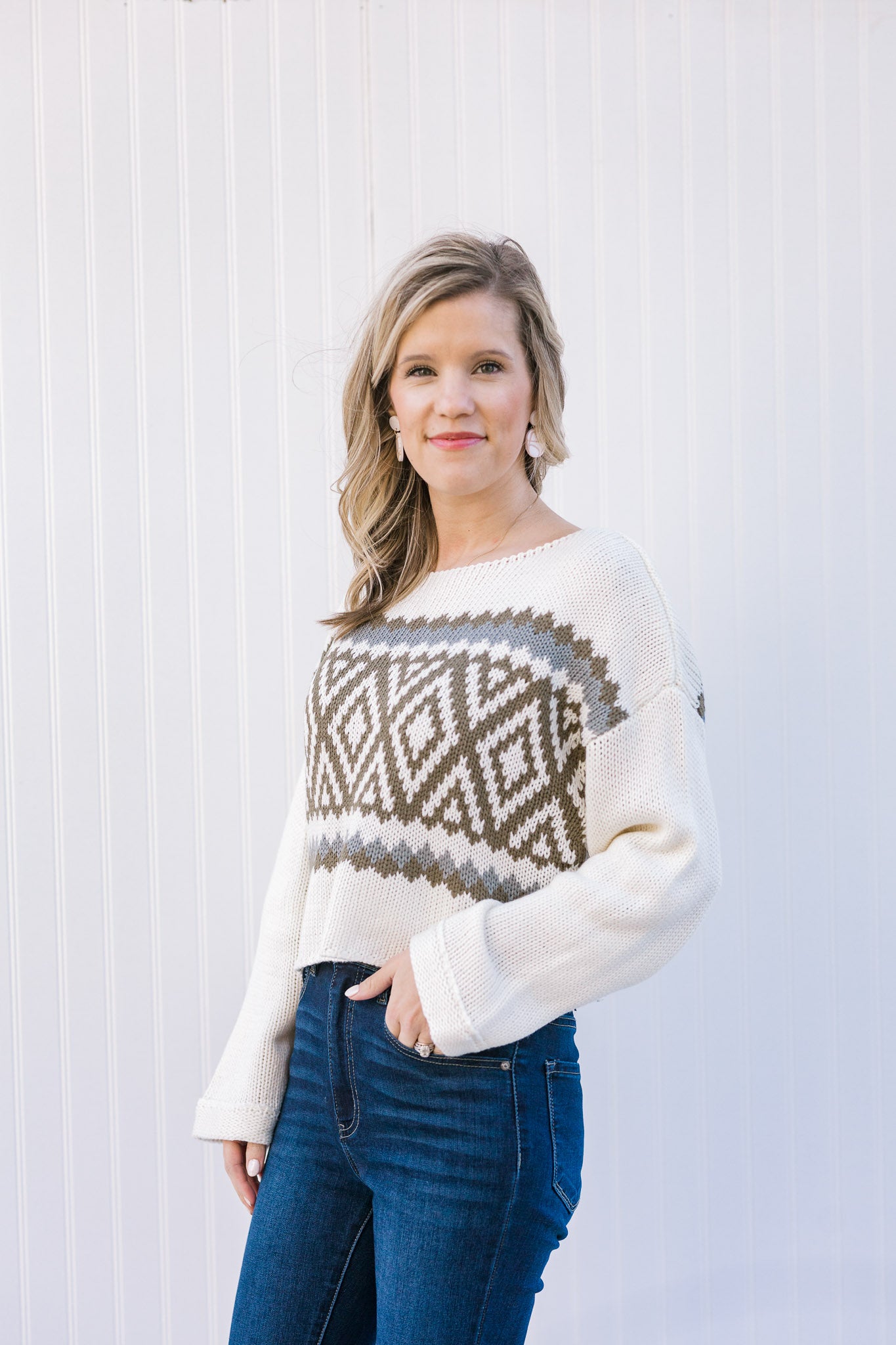 Blonde model wearing a cream sweater with a crop hem.  