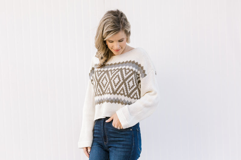 Blonde model wearing a cream Nordic sweater with a crop hem and jeans.