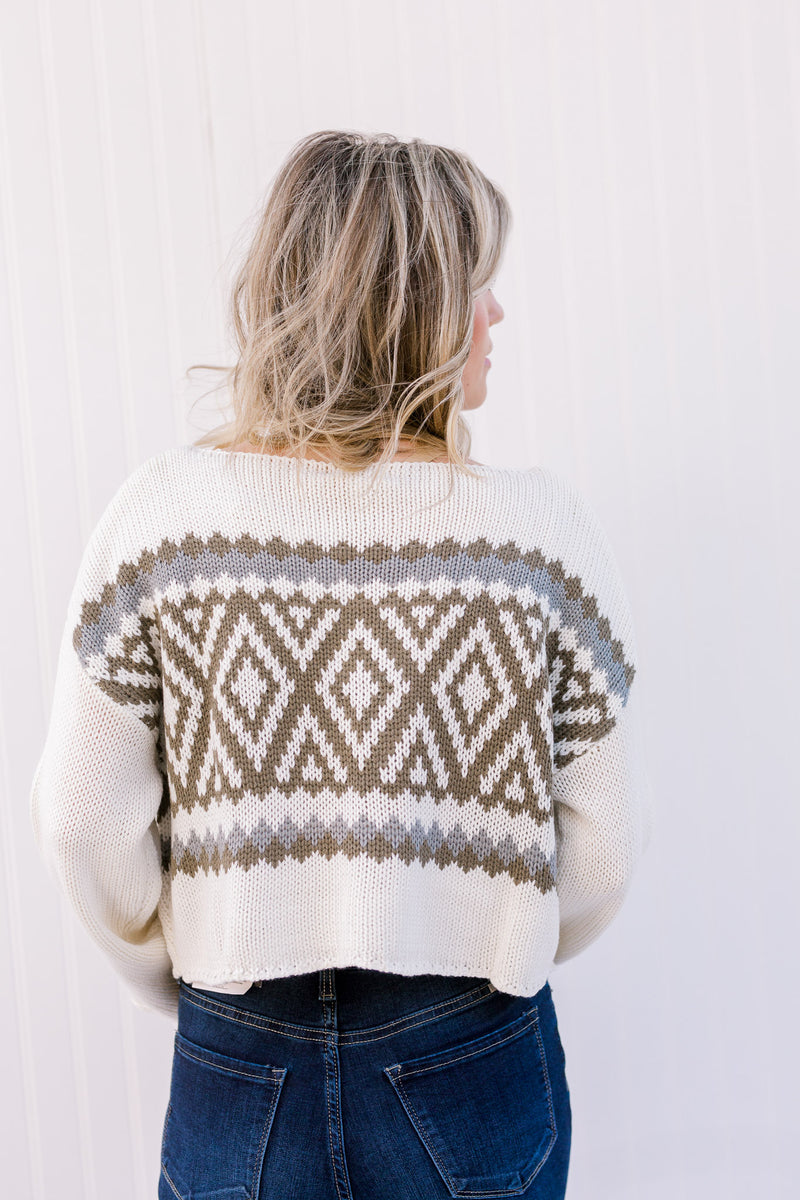 Back view of Blonde model wearing a cream sweater with a crop hem.