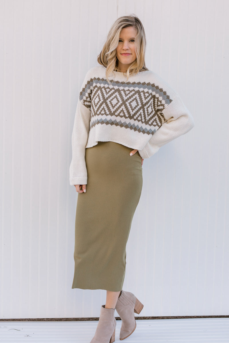 Blonde model wearing a cream Nordic sweater with a camel skirt.