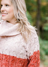 Close up view of Blonde model wearing ivory and rust sweater. 