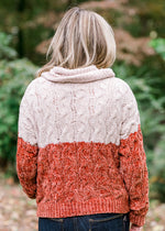 Back view of Blonde model wearing ivory and rust sweater. 