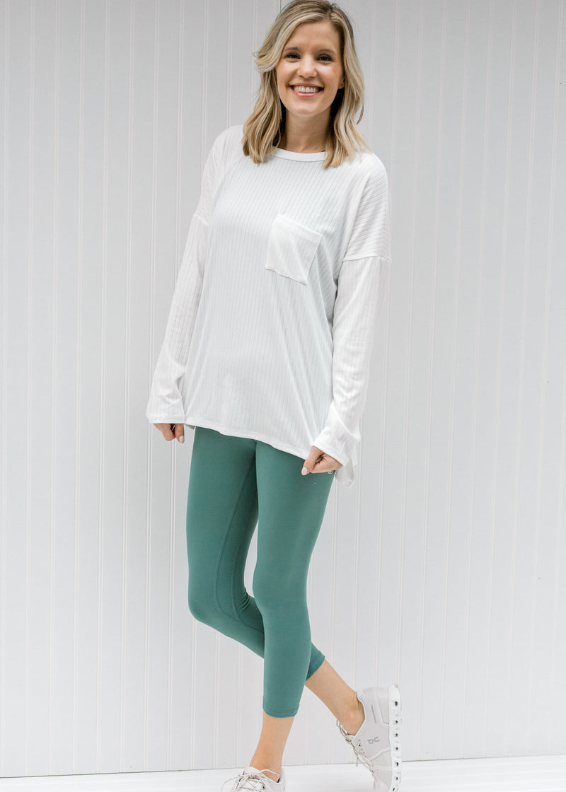 Blonde model wearing teal capri yoga pants with a white top.