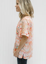 Side view of Blonde model wearing a cream top with an abstract print.