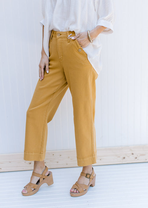 Model wearing marigold wide leg cropped jeans with button on front pockets. 