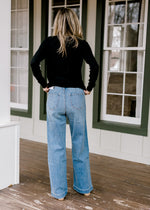 Back view of Model wearing light wash, wide leg jeans. 