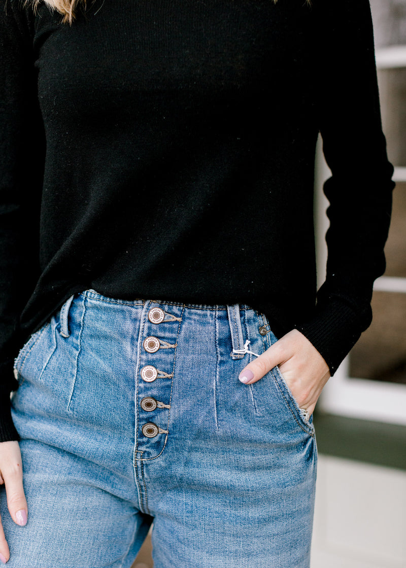 Close up view of button closure on Model wearing light wash, wide leg jeans. 