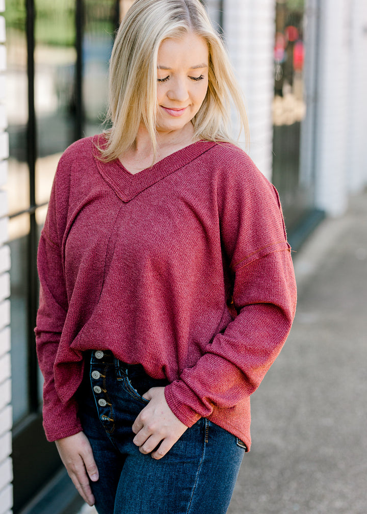 Blonde model wearing mauve, v-neck sweater.