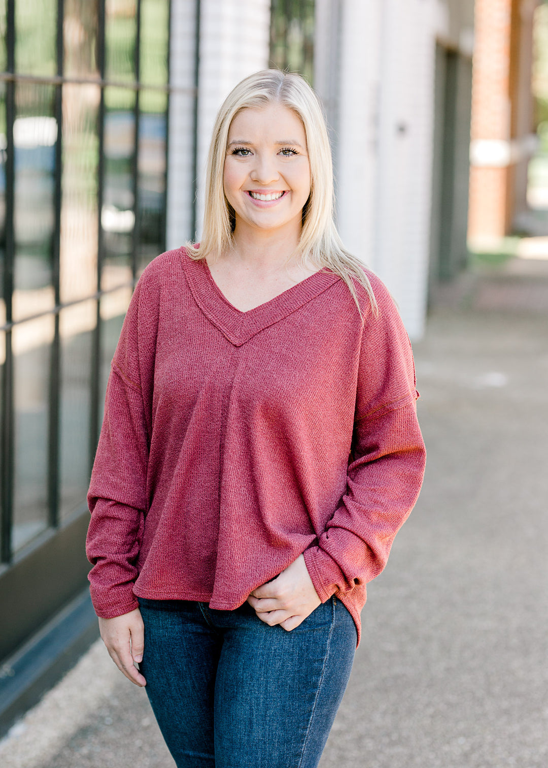 Blonde model wearing mauve sweater with jeans.
