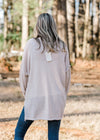 BAck view of Blonde model wearing a taupe sweater with black stars.