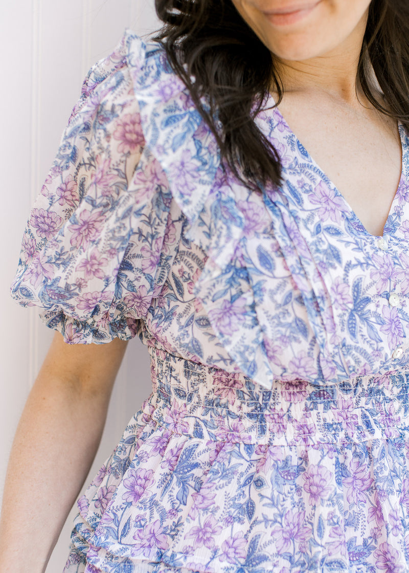 Close up view of smocked waistband and bubble short sleeves on a white top with lavender floral.