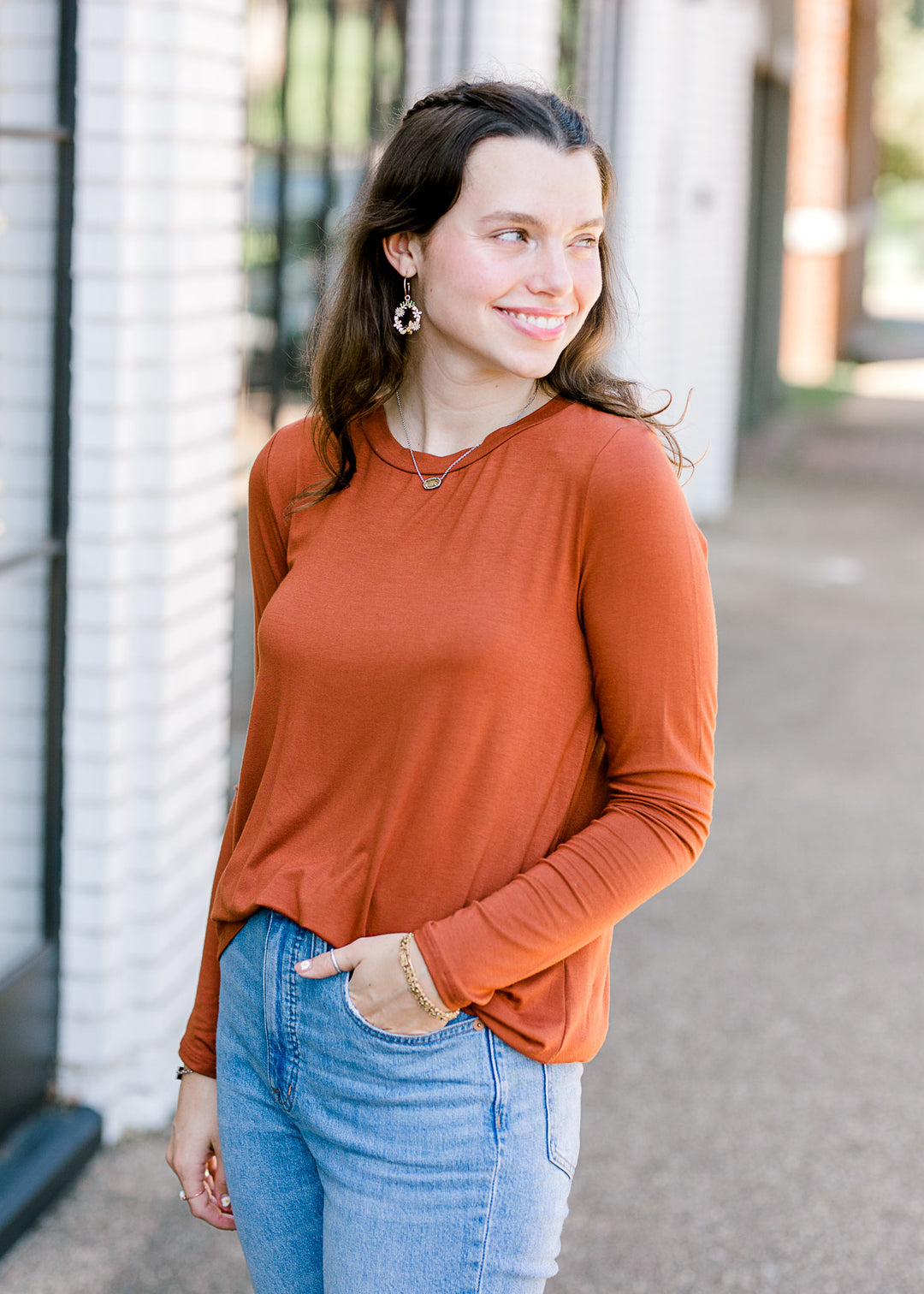 Brunette model wearing deep mauve long sleeve top. 