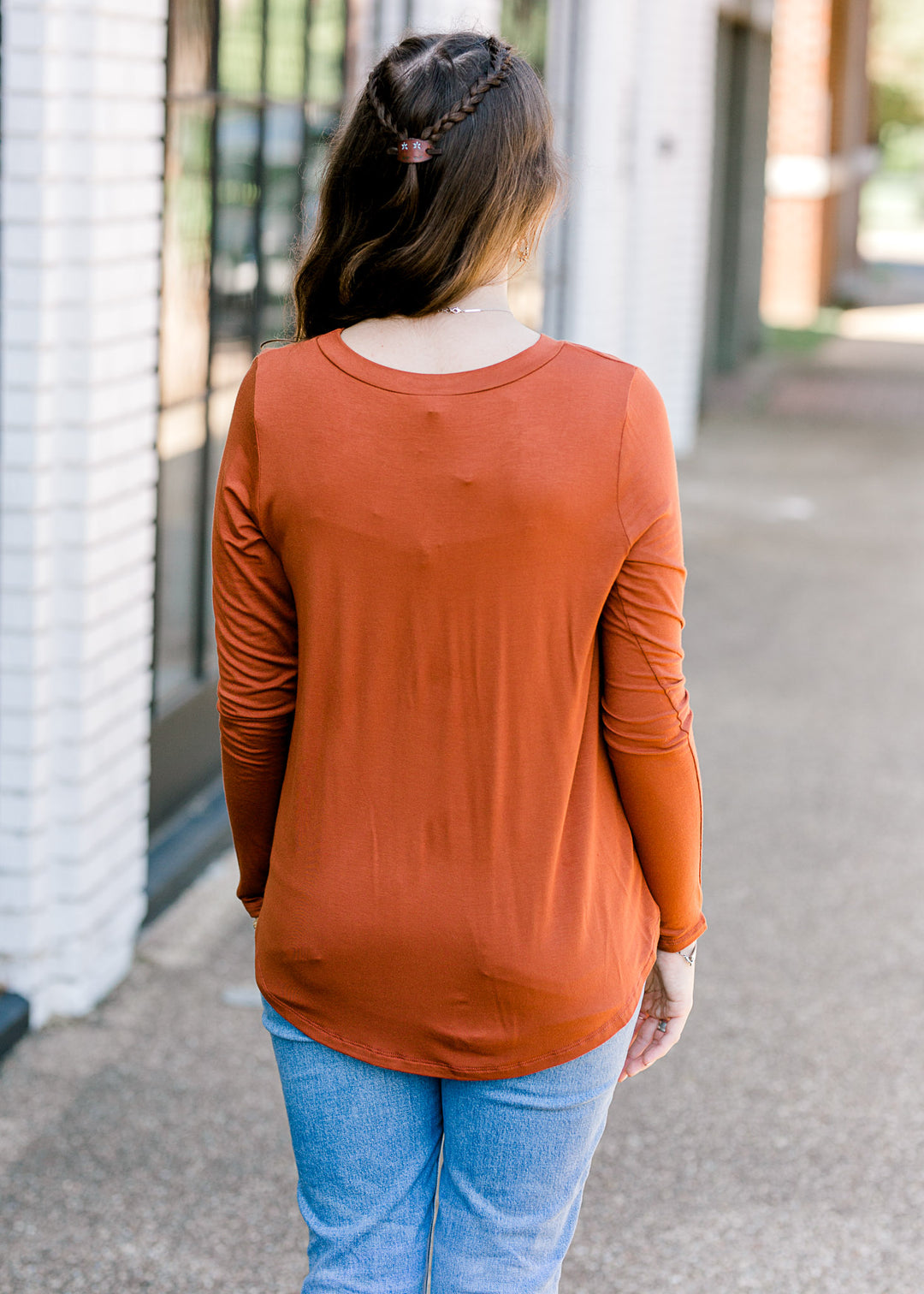 Back view of Brunette model wearing deep mauve long sleeve top.