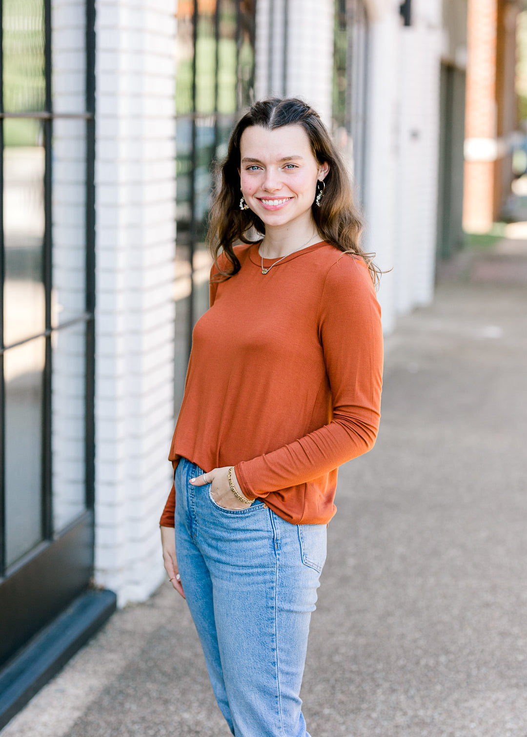 Brunette model wearing deep mauve long sleeve top tucked in front.