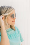 Side view of Model wearing back sunglasses with a gold wire rim.