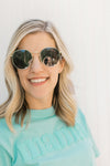 Close up view of Model wearing back sunglasses with a gold wire rim.