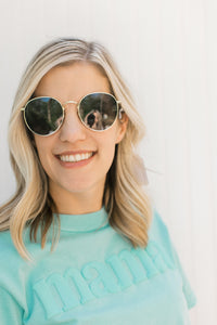 Close up view of Model wearing back sunglasses with a gold wire rim.