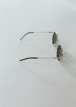 Side view of round sunglasses with gold rim. 
