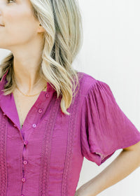 Close up view of lace detail on bodice of a magenta short sleeve button up dress. 